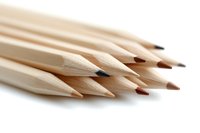 Sharp wooden pencils arranged in diagonal composition on white background, close-up macro photography showing texture and detail of graphite tips and natural wood grain.