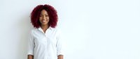 Professional African American businesswoman with curly red hair wearing white shirt smiling confidently against clean background for corporate marketing materials.