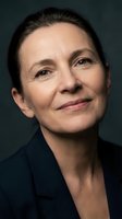 Middle-aged woman with short dark hair and fair complexion wearing black blazer against dark background. Professional headshot for corporate, business, and executive portraits.