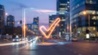 Glowing neon checkmark symbol in futuristic holographic frame floating over blurred city street at dusk with bokeh lights and modern skyscrapers in background.