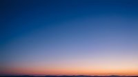 Stunning gradient sky transitioning from deep blue to warm orange hues during golden hour twilight for backgrounds and design projects.