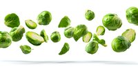 Fresh brussels sprouts flying in air on white background, whole and halved green vegetables for healthy cooking and food design.