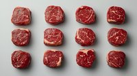Raw beef steaks arranged in rows on white background, fresh red meat cuts for cooking, butcher shop display, culinary ingredients for grilling and roasting.