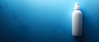 White plastic bottle with spray nozzle on dramatic blue gradient background with copy space for product placement and branding designs.