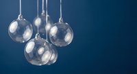 Clear glass Christmas ornaments hanging on silver strings against deep blue background for holiday decorations and festive seasonal displays.