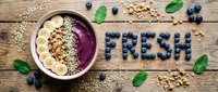 Acai smoothie bowl topped with banana, granola, and hemp seeds on rustic wood, with blueberries spelling FRESH for healthy eating concepts.