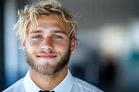 Young Caucasian businessman with blonde hair and beard wearing white shirt smiling confidently at camera in modern office environment. Professional corporate portrait.