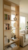 Modern wooden bookshelf with books and decor in bright living room interior. Scandinavian style furniture and home organization for contemporary apartment design.