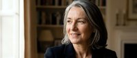 Confident mature woman with gray hair smiling warmly in elegant home interior, representing successful aging, wisdom and professional achievement in lifestyle portrait.