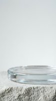 Empty glass petri dish on textured white surface, isolated on light background, ready for product mockups, laboratory displays, or scientific presentations.