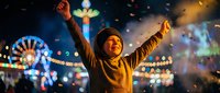 Young Asian woman celebrating with raised arms at colorful night carnival with ferris wheel and festive lights creating joyful atmosphere for entertainment events.