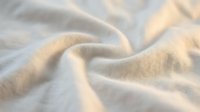 Soft beige fabric with delicate folds and natural texture, ideal for textile, fashion, and interior design projects requiring warm, neutral material backgrounds.