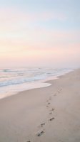 Serene beach scene with footprints in sand leading along shoreline during pastel sunset with gentle waves and soft pink sky colors.
