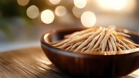 Wooden toothpicks in brown ceramic bowl against blurred bokeh background with warm lighting, shallow depth of field creates elegant dining atmosphere.