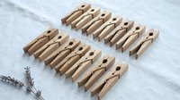 Natural wooden clothespins arranged in rows on white linen fabric with dried lavender sprigs for laundry organization and home decor projects.