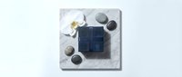Elegant spa composition with navy blue soap bars, smooth stones and white orchid flower on marble surface for wellness and relaxation concepts.