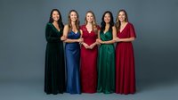 Five diverse women in elegant formal gowns standing together against gray background for special occasions, celebrations, and formal events.