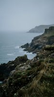 Dramatic rocky coastline with rugged cliffs overlooking misty ocean waters on overcast day creating moody atmospheric seascape for travel and nature content.