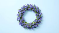Lavender wreath with purple flowers and green stems on light blue background for home decor and seasonal decoration projects.