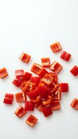 Freshly diced red bell pepper pieces scattered on white background, isolated for food blogs, recipe cards, and healthy eating content.