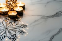 Glowing candles and decorative snowflake on white marble surface create cozy winter atmosphere. Warm candlelight reflects festive holiday mood for seasonal design.