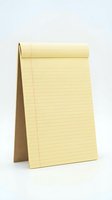 Yellow lined notepad with cardboard backing isolated on white background for office supplies and stationery design projects.