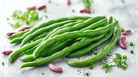 Fresh green string beans with garlic cloves and herbs on light background, ready for cooking healthy vegetable dish.