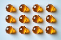 Amber glass spheres arranged in neat rows on white background, creating uniform shadow pattern. Isolated objects for cosmetic, pharmaceutical, or supplement concept.