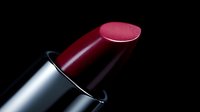 Luxury burgundy lipstick with metallic silver case on black background for cosmetics and beauty product photography.