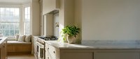 Modern farmhouse kitchen with white cabinetry, marble countertop, stainless steel range hood, and natural light from large windows. Interior design and home decor.