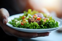 Fresh green salad with quinoa, cherry tomatoes and mixed lettuce leaves served on white plate. Healthy vegetarian meal with natural lighting.