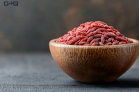 Raw ground beef mince in wooden bowl on dark surface. Fresh red meat for cooking burgers, meatballs and various culinary dishes.