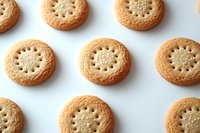 Round butter cookies with decorative holes arranged in neat rows on white background. Fresh baked shortbread biscuits showing crispy golden edges and pale centers.