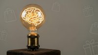 Vintage Edison bulb with warm glowing filament on wooden base against neutral background for retro lighting design and home decor projects.