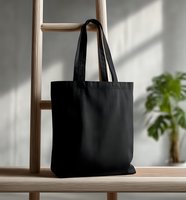 Black cotton tote bag hanging on wooden ladder with natural light and plant in background, eco-friendly shopping alternative for everyday use.