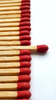 Red wooden matchsticks arranged in neat row with one standing out from group on white background for leadership and individuality concepts.