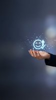 Hand holding glowing neon smiley face with upward arrow icon surrounded by sparkling particles on dark background, representing customer satisfaction, positive feedback, and business growth.