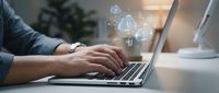 Professional businessman typing on laptop with digital security icons and cybersecurity symbols floating above keyboard in modern office workspace.