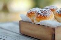 Fresh homemade sweet buns dusted with powdered sugar served in wooden box on rustic table, selective focus with soft bokeh background for food photography.