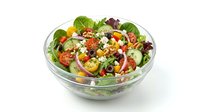 Fresh vegetable salad with mixed greens, tomatoes, cucumbers, and chickpeas in glass bowl, ready for healthy eating or restaurant menu use.