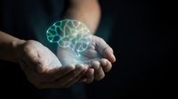 Hands holding glowing digital brain hologram representing artificial intelligence, machine learning, neuroscience and cognitive technology innovation.