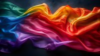 Flowing rainbow silk fabric with elegant waves and folds creating dynamic movement against dark background. Vibrant spectrum of colors from red to blue in smooth textile.