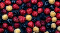 Fresh ripe raspberries in red, golden and blackberries arranged in pattern on dark background, organic summer berries macro photography for food design.