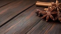Aromatic star anise spices and cinnamon stick arranged on rustic dark wooden background for culinary cooking and baking recipes.