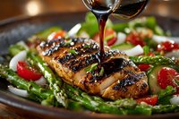Grilled chicken breast with balsamic glaze served on bed of fresh asparagus, cherry tomatoes and mozzarella salad, close-up view of gourmet meal.
