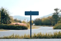 Empty blue street sign post against blurred natural landscape with grass in foreground and mountains in background, creating minimalist composition for copy space.