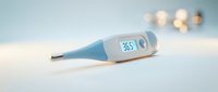 Digital thermometer displaying 36.5 degrees on white surface with soft bokeh background, medical healthcare temperature measurement tool for fever detection and wellness monitoring.