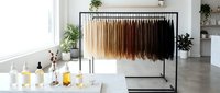 Modern minimalist clothing rack with earth tone garments in bright contemporary interior with plants and natural light for fashion retail display.