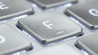 Close-up of metallic keyboard key with F letter, shallow depth of field showing chrome button detail for technology, computing, and office work concepts.