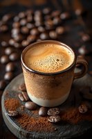 Fresh espresso with golden crema in ceramic cup on dark wooden board, surrounded by roasted coffee beans and ground coffee powder, moody lighting.
